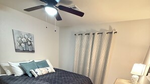 A bedroom with a bed, a ceiling fan, a nightstand, a lamp, and a rug.