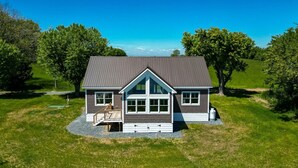Ein zweistöckiges Haus mit großer Veranda, geneigtem Dach und gepflegtem Rasen.