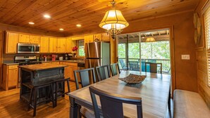 A wooden interior with a kitchen, dining area, and large windows. - Ultimate Entertainment Cabin w/ Theater & Game Room! (Martin)