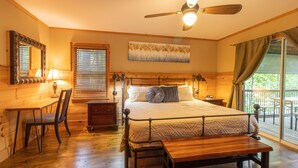 A bedroom with a wooden bed, a desk, a chair, a bedside table, a ceiling fan, and a window with curtains. - Ultimate Entertainment Cabin w/ Theater & Game Room! (Martin)