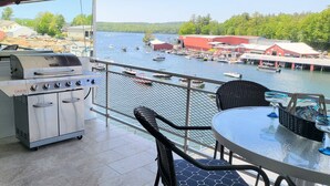Ein Balkon mit Grill, Stühlen und Tisch mit Blick auf eine Marina und Gebäude mit Booten.