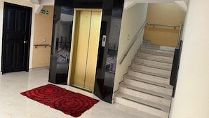 A hotel lobby with a staircase, a black door, and a red carpet. - Hotel Bosque Chapinero (Bogotá)