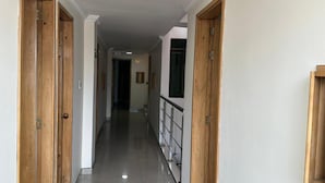 A hallway with wooden doors on both sides, a tiled floor, and a staircase at the end. - Hotel Bosque Chapinero (Bogotá)