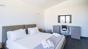 Une chambre d’hôtel moderne, dotée d’un grand lit, d’un bureau, d’une chaise et d’une petite table ronde.
