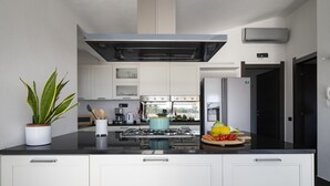 Une cuisine moderne avec des meubles blancs, un îlot central, une cuisinière et un réfrigérateur.