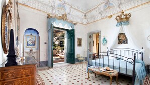 A bedroom with a four-poster bed, a wooden dresser, a mirror, and a chandelier. - Palazzo Crocione in Positano (Positano)