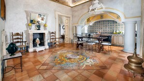 A spacious room with a tiled floor, a fireplace, a dining area, and a kitchen. - Palazzo Crocione in Positano (Positano)