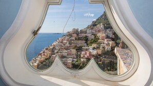 A view from a window overlooking a coastal town with colorful buildings and a clear blue sea. - Palazzo Crocione in Positano (Positano)