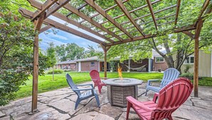 En udendørs terrasse med Adirondack-stole, pejse og en pergola.