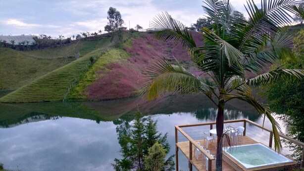 A serene lakeside setting with a wooden deck and a hot tub. - Cabin 1 - Dakeva (El Peñol)