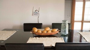 A dining table with a bowl of oranges, a glass vase, and a sign on the wall. - Cabin 1 - Dakeva (El Peñol)