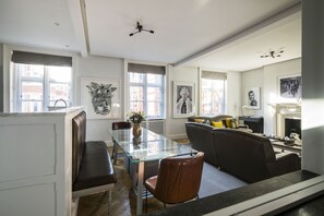 Uma sala de estar moderna com mesa de jantar de vidro, sofás de couro e lareira.