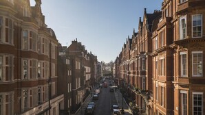 A street lined with historic buildings, a clear sky, and parked cars.