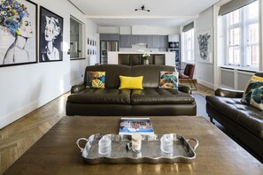 A modern living room with a dark leather sofa, a coffee table with a tray, and a magazine. - The Connaught Suite in London (London)