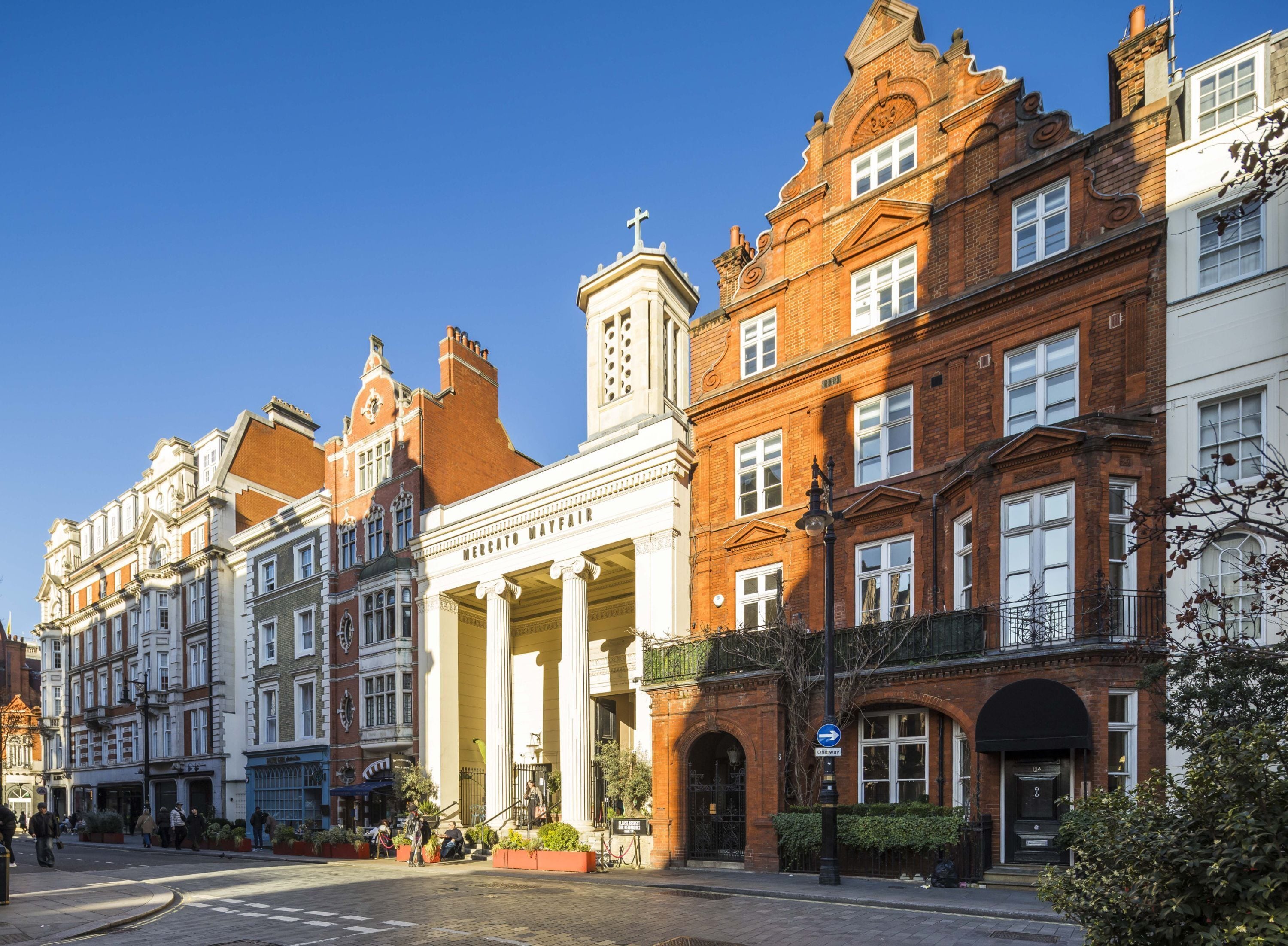 A row of historic buildings with classical architecture, including a prominent building with columns labeled "Mercato Mayfair."