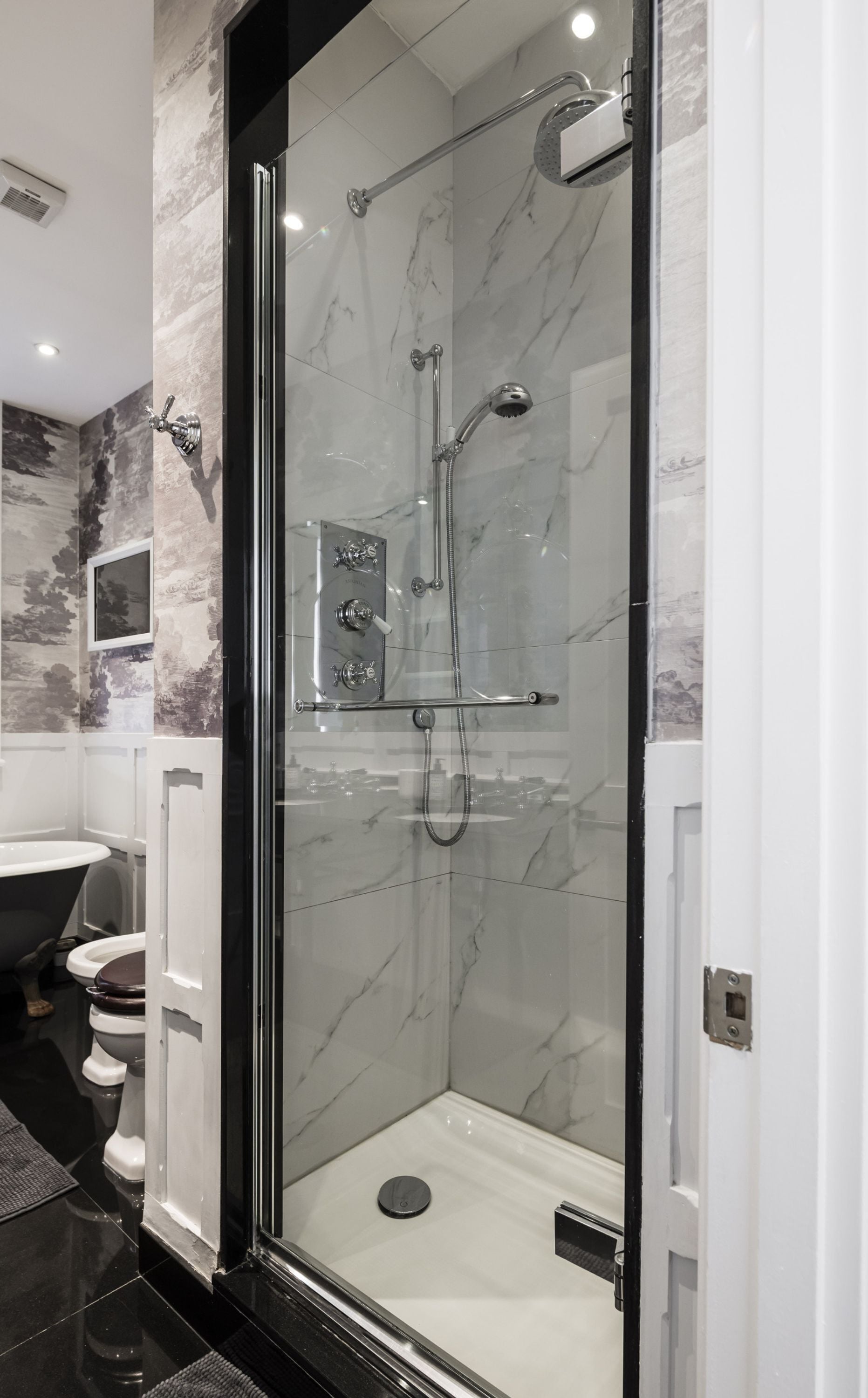 Een moderne badkamer met een douchecabine van glas, een witte wastafel en een toilet.