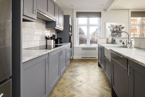Uma cozinha moderna com armários cinza, azulejos brancos e piso de madeira em padrão herringbone.