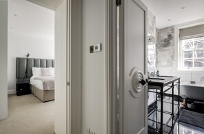 A modern bedroom with a bed, bedside table, and a bathroom with a bathtub and sink.