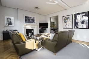 A modern living room with a fireplace, leather sofa, flat-screen TV, and artwork on the walls. - The Connaught Suite in London (London)