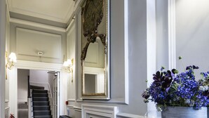 A hallway with a fireplace, a mirror, and a potted plant. - The Connaught Suite in London (London)