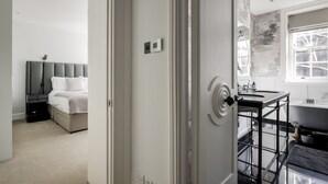 A modern bedroom with a bed, bedside table, and a bathroom with a bathtub and sink. - The Connaught Suite in London (London)