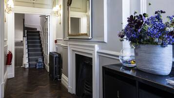 A hallway with a fireplace, a mirror, and a potted plant.