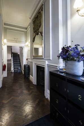 A hallway with a fireplace, a mirror, and a potted plant. - The Connaught Suite in London (London)