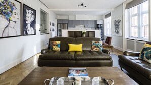 A modern living room with a dark leather sofa, a coffee table with a tray, and a magazine. - The Connaught Suite in London (London)