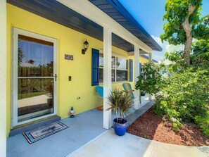 A yellow building with a blue door, a number '205' sign, and a blue chair outside.