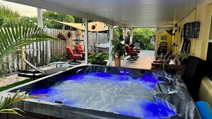 A hot tub under a covered patio with outdoor furniture and a wooden fence in the background. - Private Beach House Paradise (Melbourne Beach)