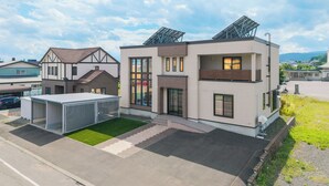 A modern two-story building with a flat roof, large windows, and a covered outdoor area. - THE BEEHIVE KAMIFURANO (Kamifurano)
