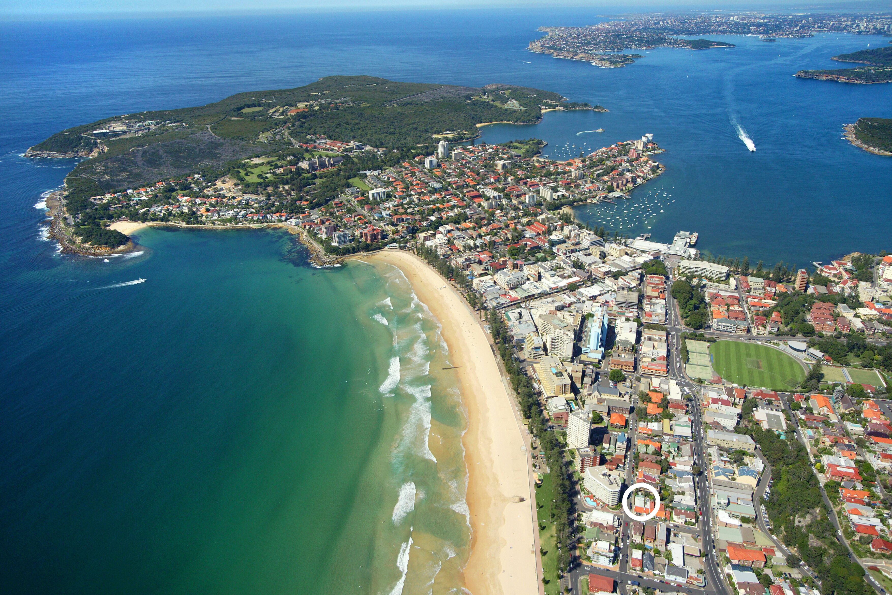 An aerial view of a coastal city with a beach, residential areas, and a marina.