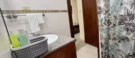 A bathroom with a granite countertop, a sink, a mirror, and a shower curtain with a leaf pattern.