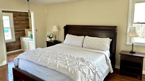 Une chambre à coucher avec un lit en bois, un ventilateur de plafond, une table de chevet avec une lampe et une fenêtre donnant sur un beau paysage.