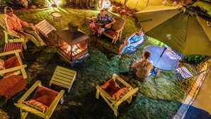 Un espace extérieur accueillant avec un foyer, des chaises en bois et une table.