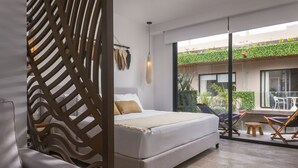 A modern bedroom with a large bed, a sofa, and a balcony with plants and outdoor furniture. - Menesse PH (Tulum)