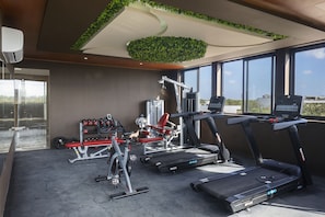 Un gimnasio moderno con cintas de correr, máquinas de pesas y un banco para press de banca.