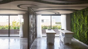 A modern interior with a glass partition, two white benches, and a green wall. - Menesse PH (Tulum)