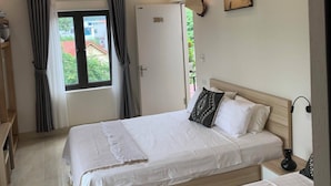 Camera d'albergo con due letti, una porta che dà all'esterno, una finestra con tende e un'opera d'arte appesa al muro.