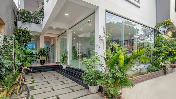 Un edificio moderno con ingresso in vetro, area salotto esterna e piante in vaso.