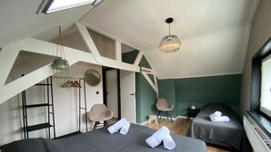 Un dormitorio moderno con dos camas, un tragaluz, una lámpara colgante y vistas al exterior.