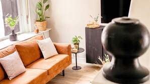 Una sala de estar moderna con un sofá, plantas en macetas, una mesita y un televisor.
