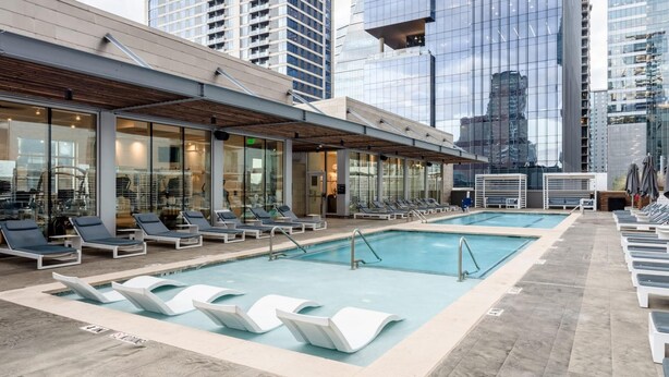 A rooftop pool area with lounge chairs and a glass-enclosed spa. - Austin Amazing 1BD 1BA 2nd Street District Apartment (Austin)