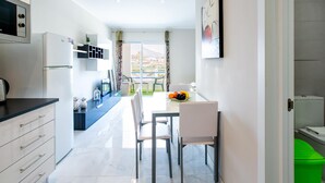 A modern kitchen with a dining area, a view of the city, and a balcony.