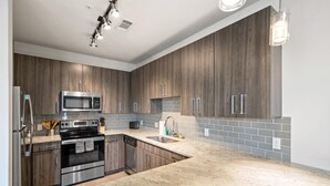 A modern kitchen with dark wood cabinets, stainless steel appliances, and a light-colored countertop.