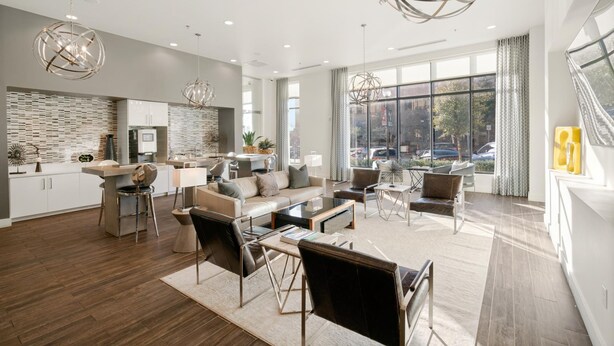 A spacious living area with a modern kitchen, large windows, and contemporary furniture.