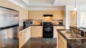 A modern kitchen with stainless steel appliances, wooden cabinets, and a granite countertop. - Austin Unique 1BD 1BA 2nd Street District Apartment (Austin)