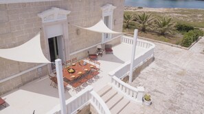 Un balcón con una mesa de comedor para seis personas, rodeado de sillas, con vistas a una playa.