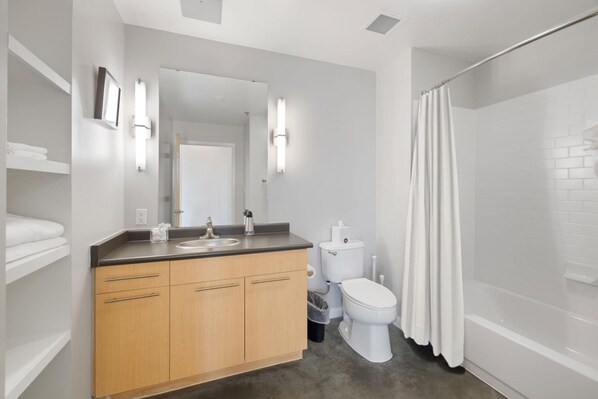 Un baño moderno con tocador de madera, accesorios blancos y zona de ducha.