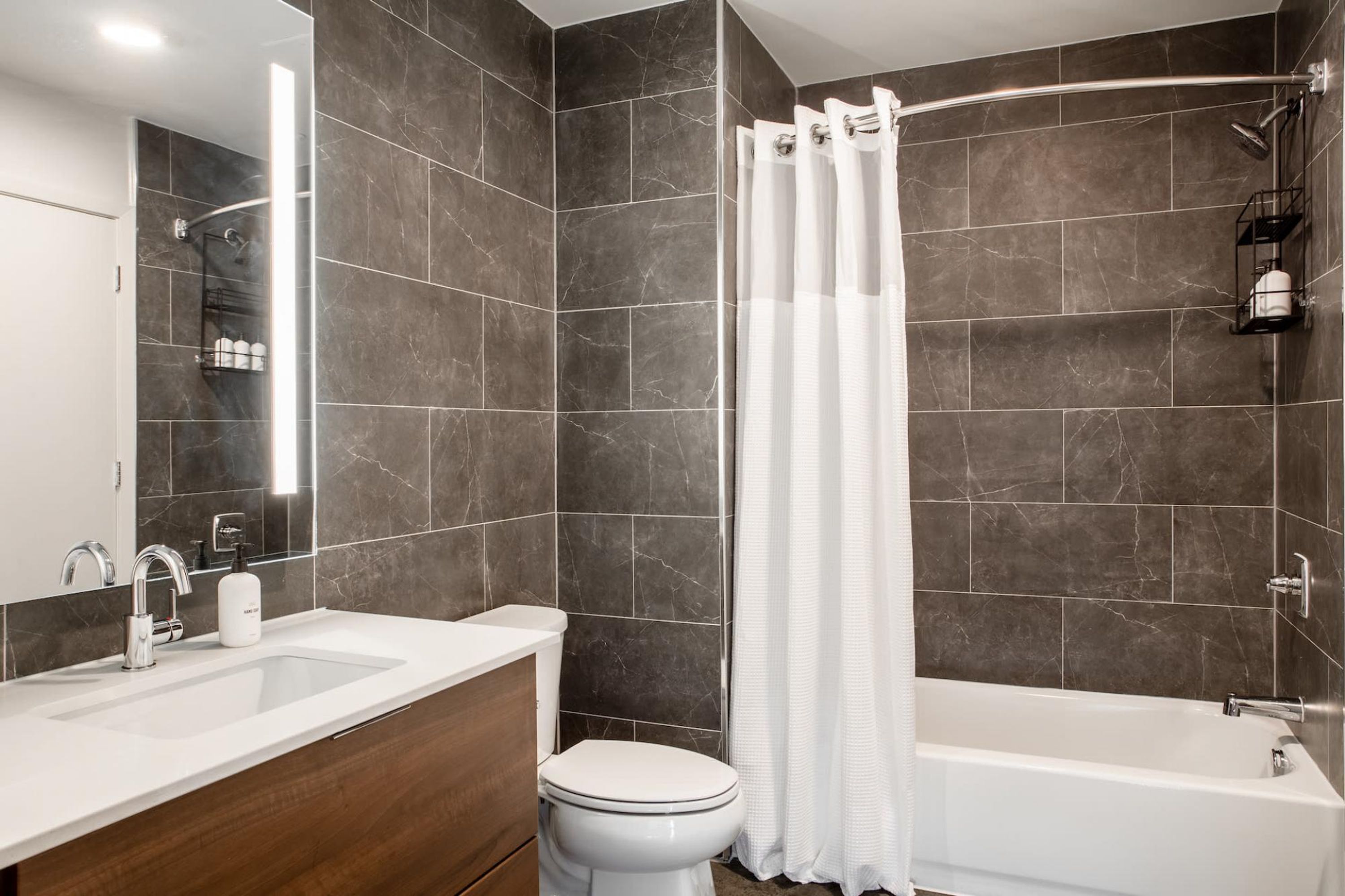 A modern bathroom with a shower, toilet, and sink.